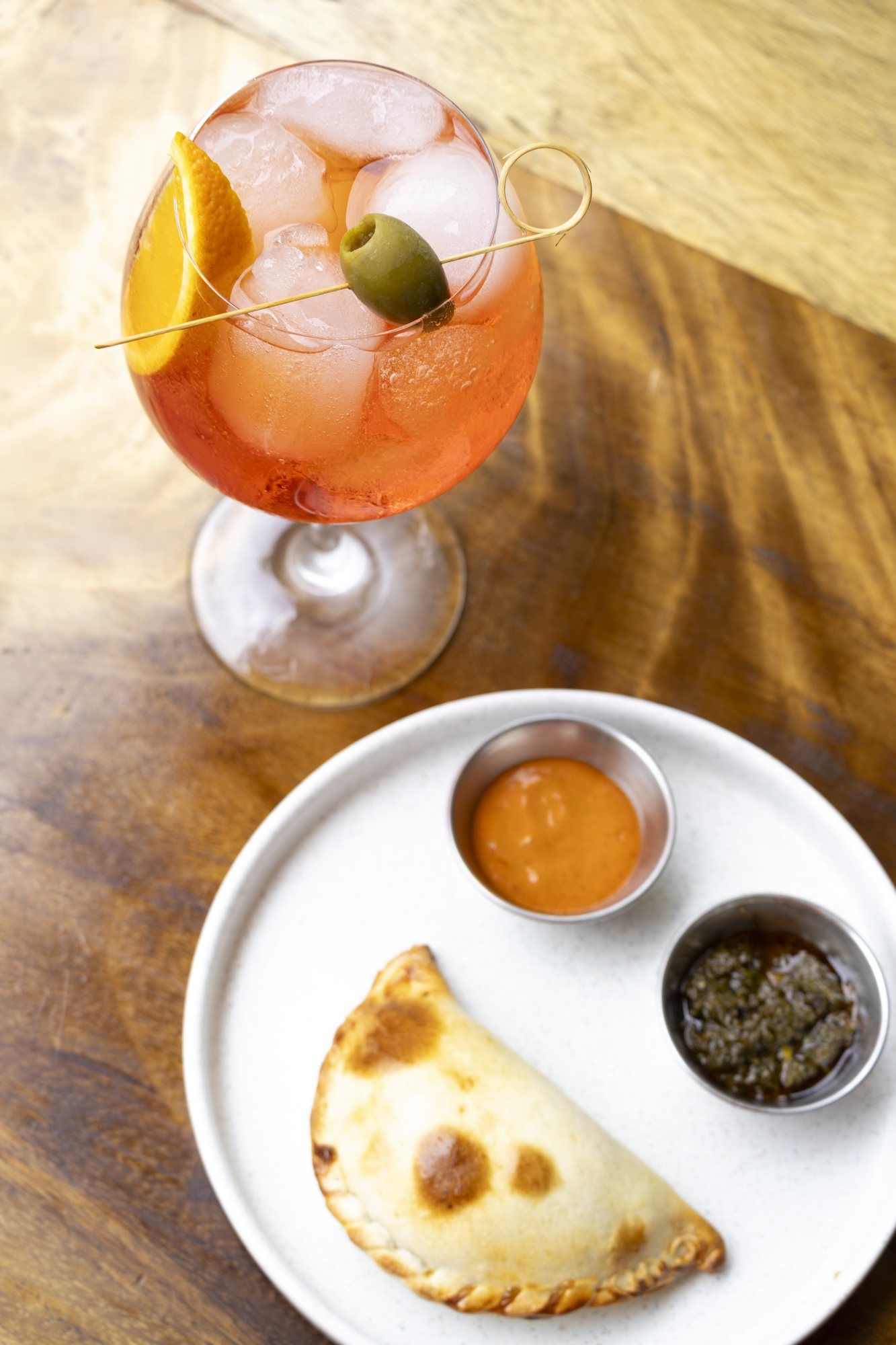 A spritz and an empanada with two sauces, seen from above