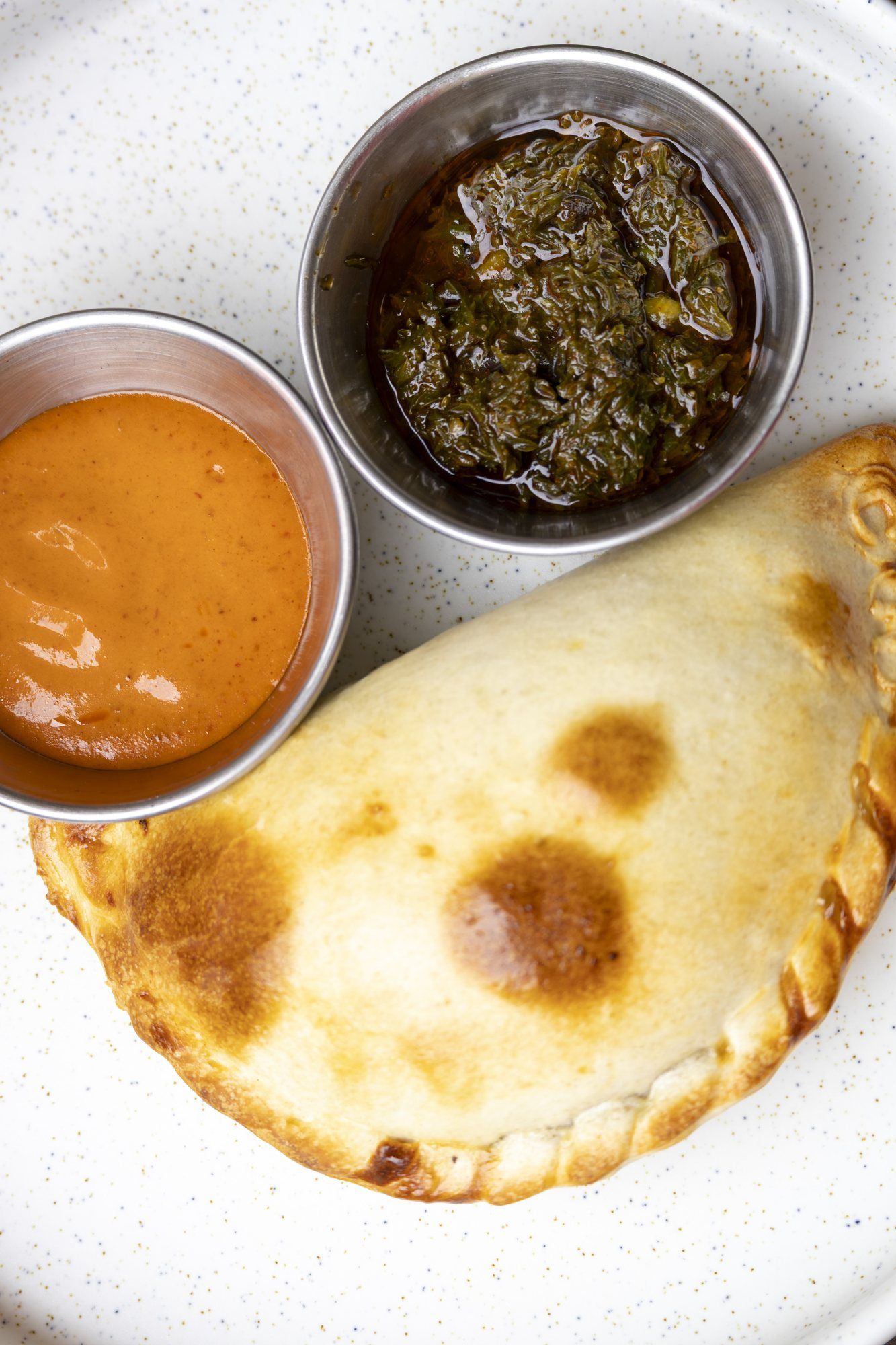 Golden empanada with two dipping sauces, seen from above